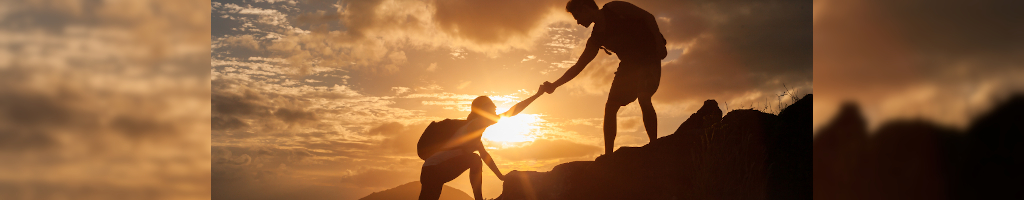 partners helping each other climb a mountain together